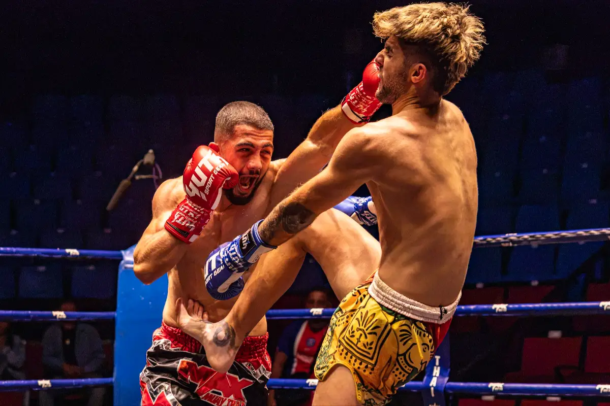 A fighter throws a knee while the other lands a punch