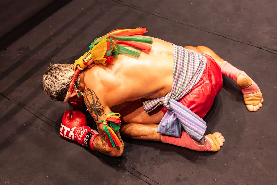 A fighter in a mongkol headband and prajiad arm cords bows to the canvas during the Wai Kru at IFL-5